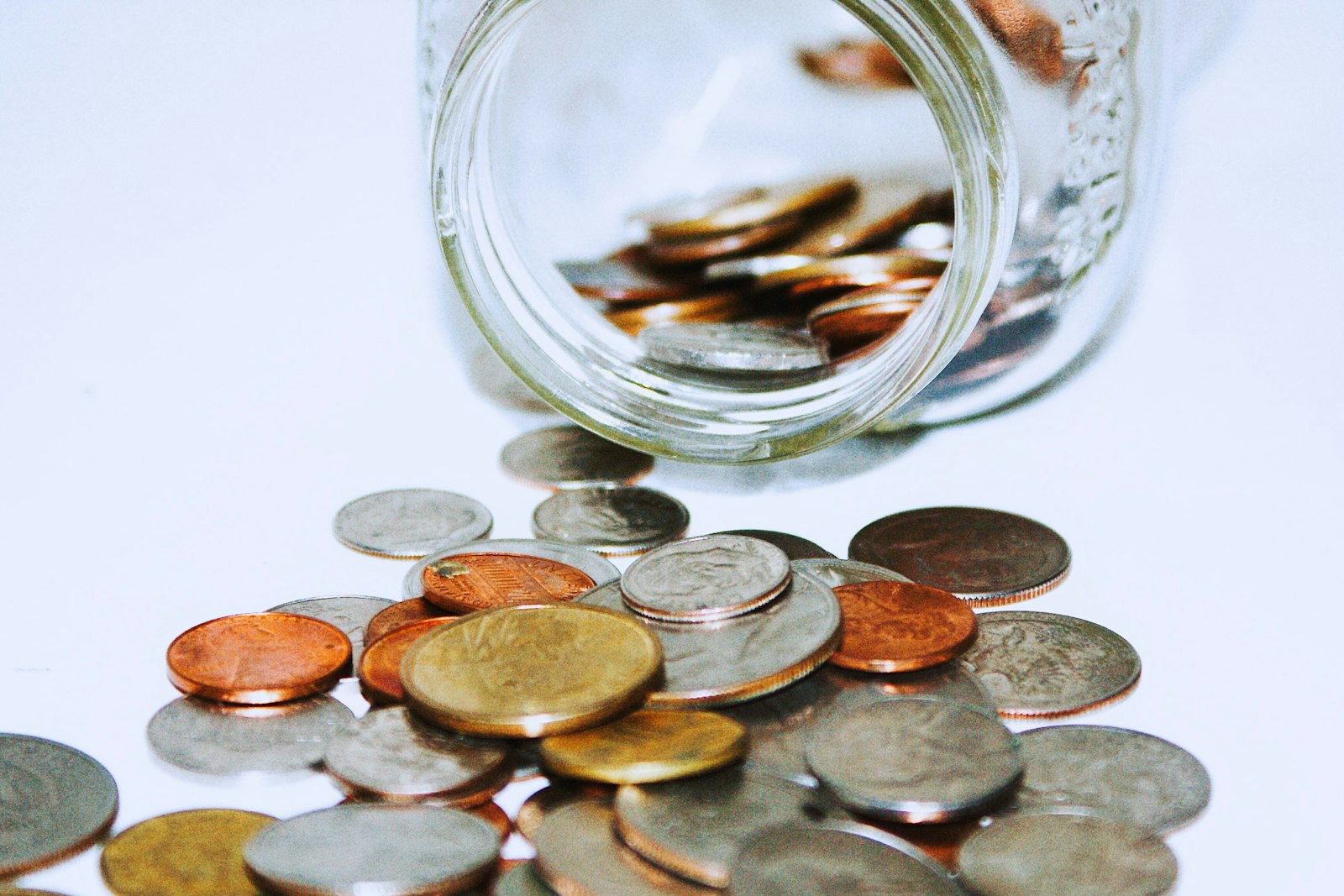 Coins spilling out of a glass jar, representing cash ISA savings
